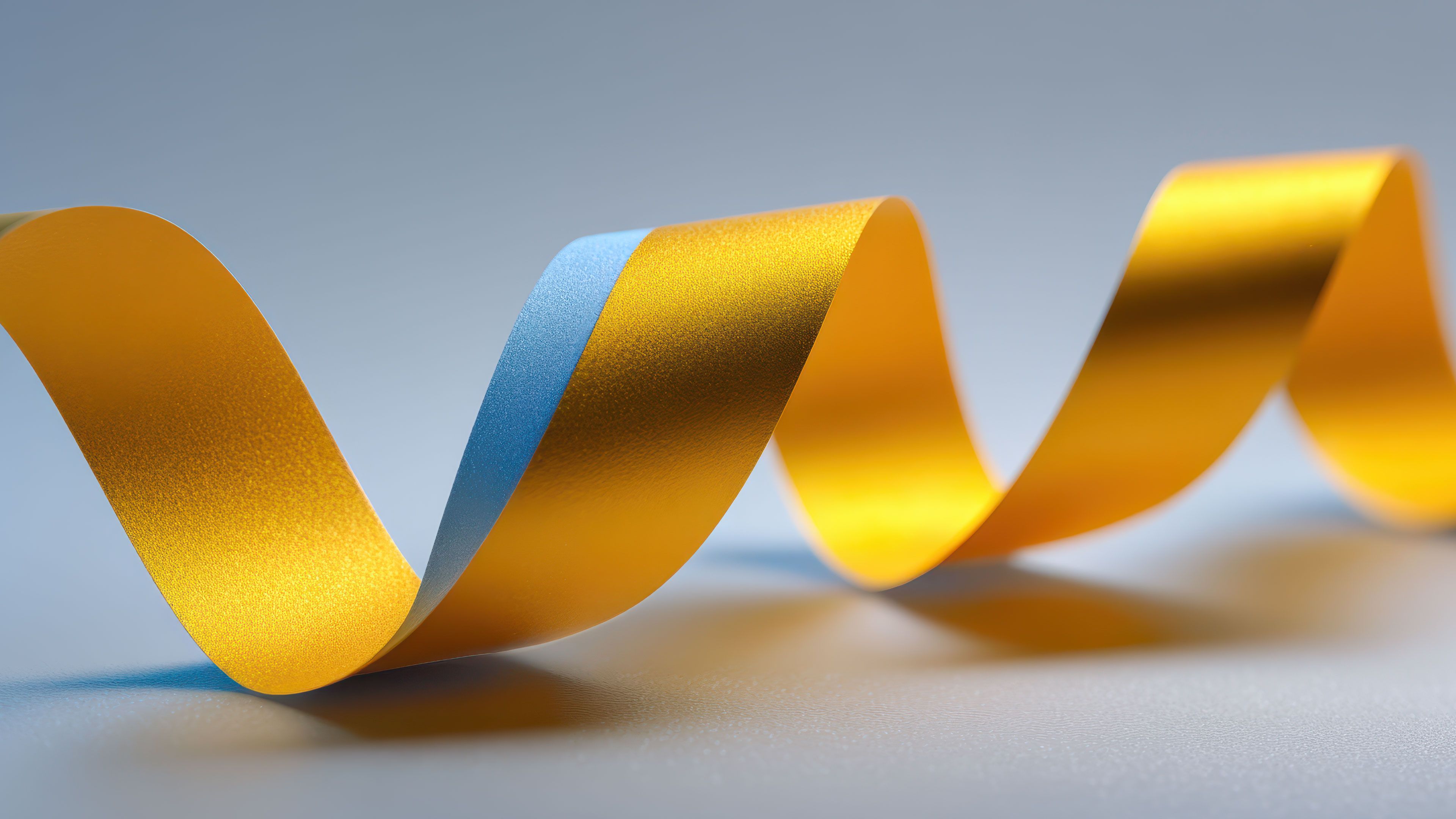 A vibrant, multicolored ribbon elegantly twists and turns against a smooth gradient background, creating a dynamic and lively visual effect that emanates a sense of motion and fluidity.