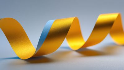 A vibrant, multicolored ribbon elegantly twists and turns against a smooth gradient background, creating a dynamic and lively visual effect that emanates a sense of motion and fluidity.