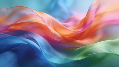 The wallpaper features flowing waves of silk in vibrant rainbow hues, creating a dynamic and colorful display. The smooth, undulating textures evoke a sense of movement and elegance, setting a lively and uplifting mood.