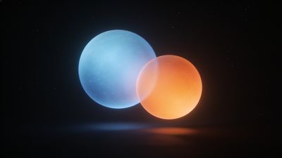 Two luminous spheres, one blue and one orange, float closely together in a dark, star-speckled space, creating an ethereal and serene atmosphere.