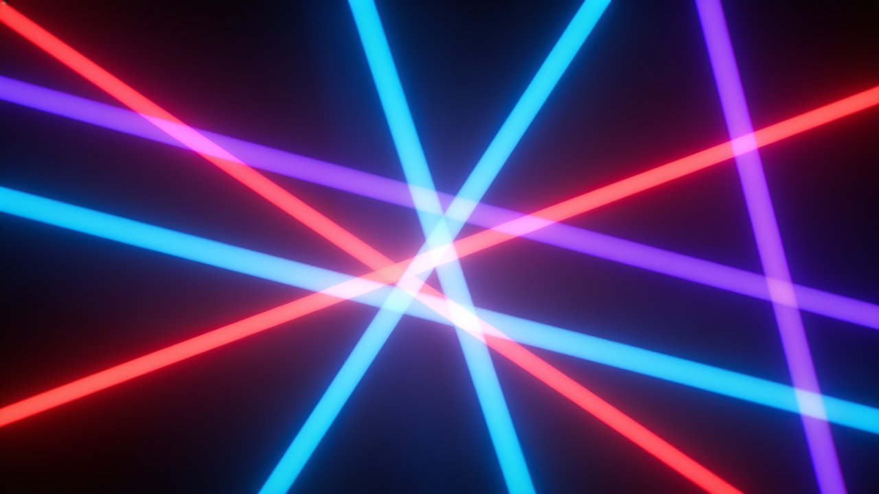 A dynamic display of intersecting neon laser beams in vibrant shades of blue, red, and purple against a dark background, creating an energetic and futuristic atmosphere.