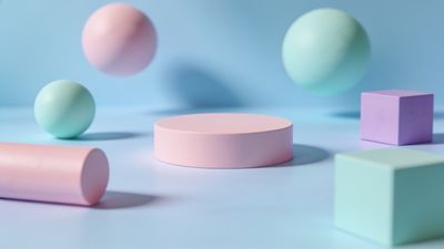 A serene composition of pastel geometric shapes, including spheres, cylinders, and cubes, is arranged on a soft blue background, creating a calm and balanced visual effect.