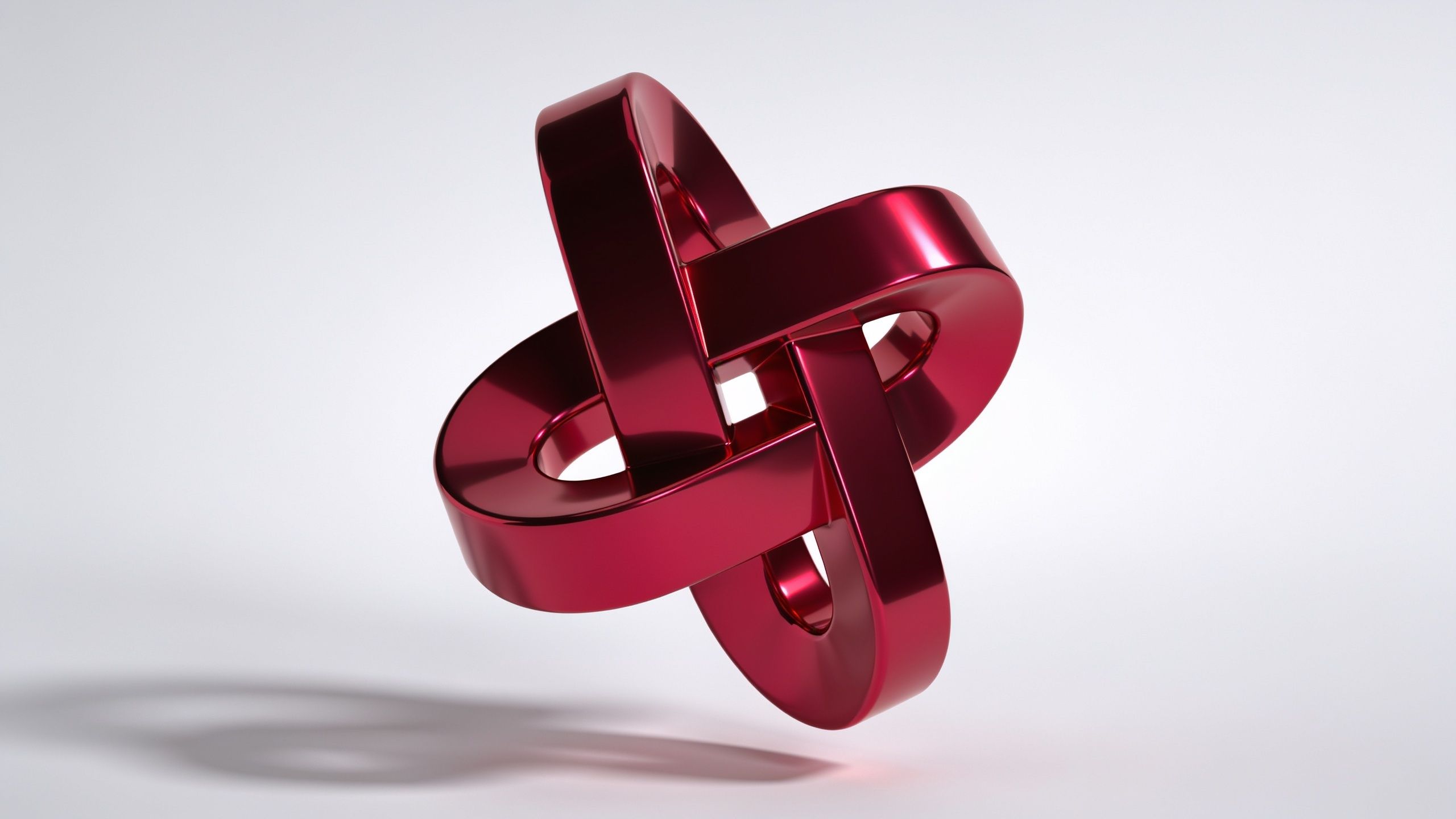 A sleek, red metallic abstract shape with intertwined loops is set against a plain white background, creating a modern and sophisticated mood. The shiny surface and intricate design evoke a sense of elegance and futuristic style.
