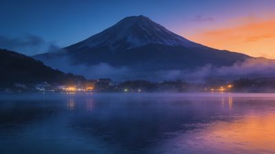 A majestic mountain rises in the background, silhouetted against a vibrant dawn sky with hues of orange and purple, while a misty lake in the foreground reflects the serene colors, creating a tranquil and peaceful atmosphere.