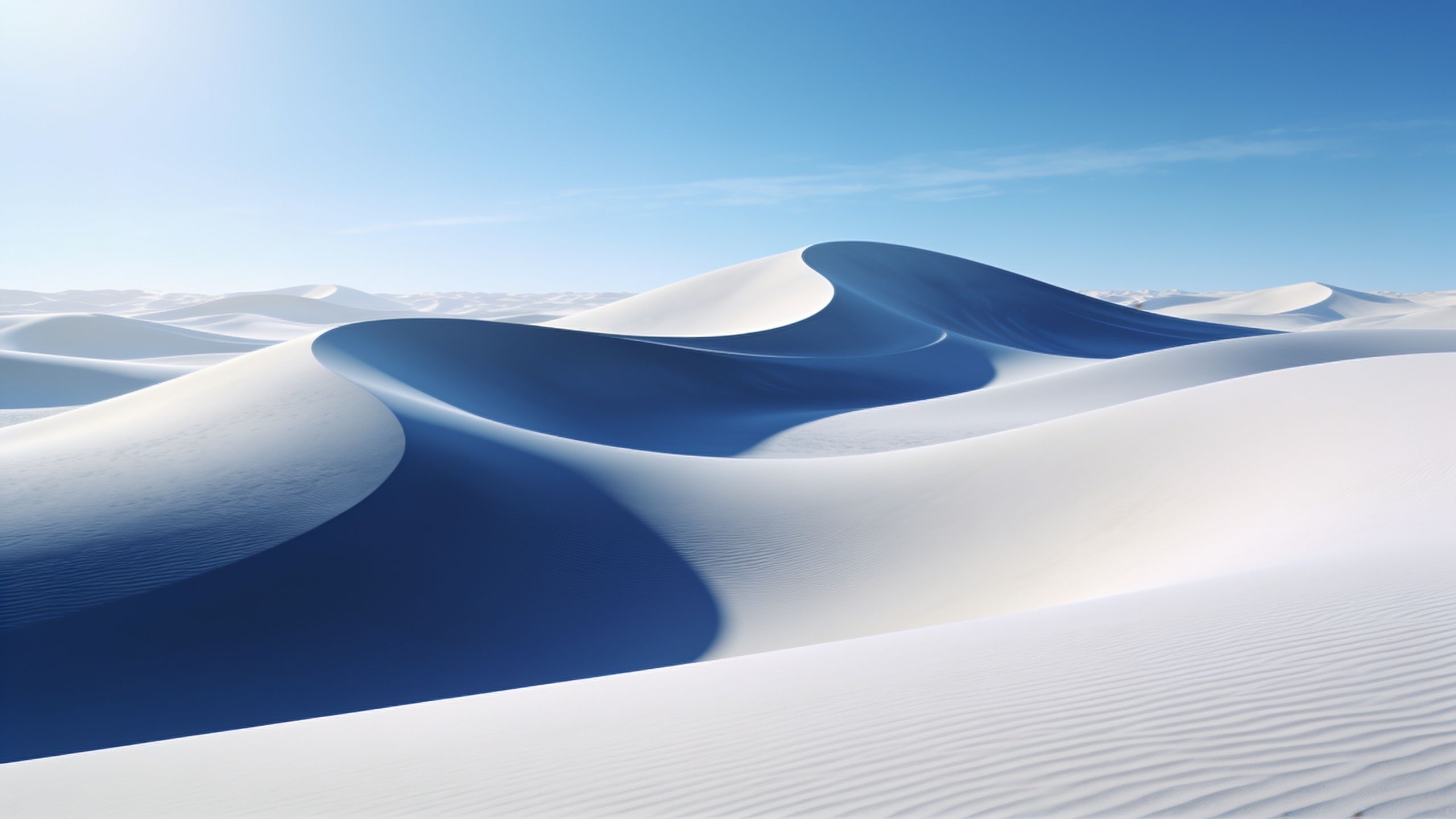 A vast expanse of smooth, blue-tinted desert dunes is bathed in the soft glow of sunrise, creating a tranquil and serene atmosphere under a clear blue sky.