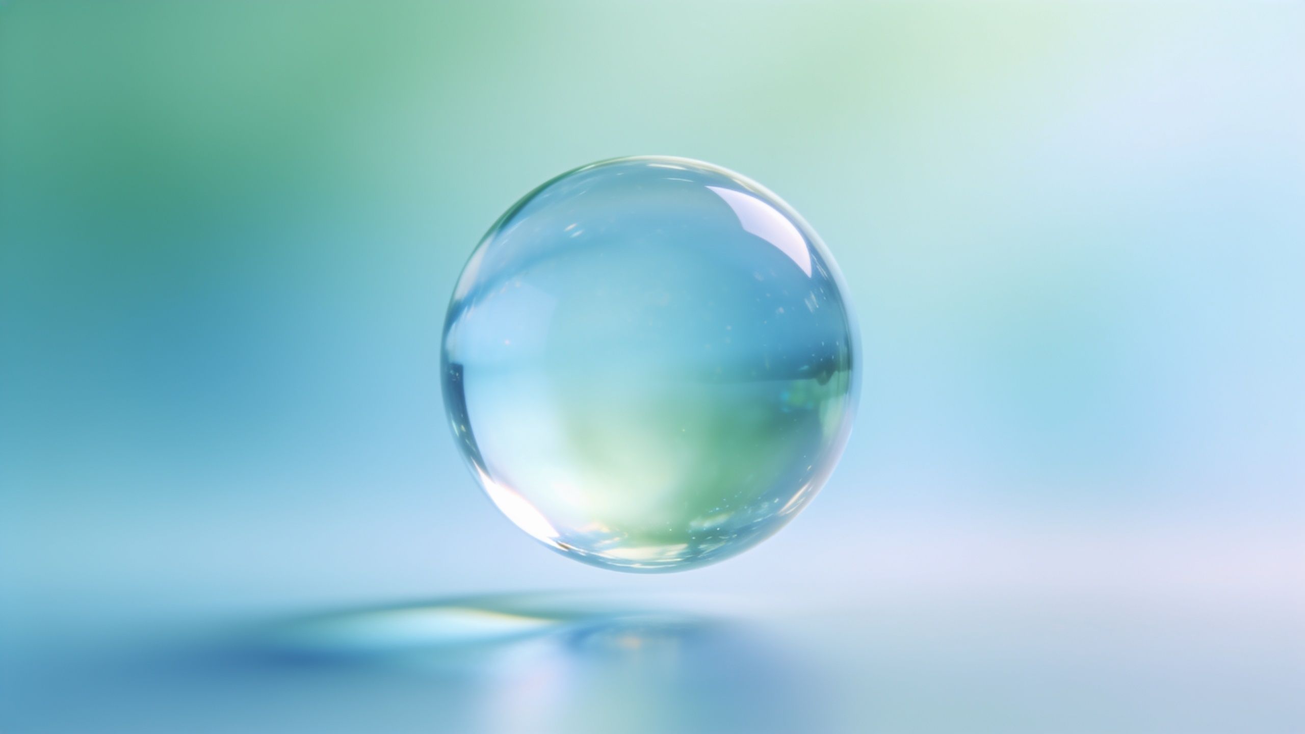 A translucent glass sphere floats gently above a soft, blurred pastel background of blue and green hues, creating a serene and ethereal atmosphere.