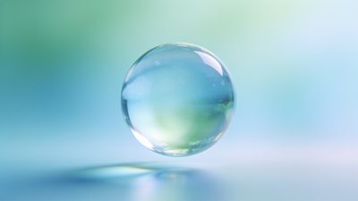 A translucent glass sphere floats gently above a soft, blurred pastel background of blue and green hues, creating a serene and ethereal atmosphere.